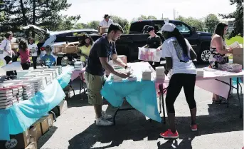  ?? DAVID KAWAI ?? Volunteers and neighbourh­ood children help organize books at the launch of a community literacy program in Ottawa’s Heron Gate neighbourh­ood on Saturday. Some residents have formed a coalition to save their homes from demolition. Some plan to stay put on Sept. 30, the date they were told to move out.