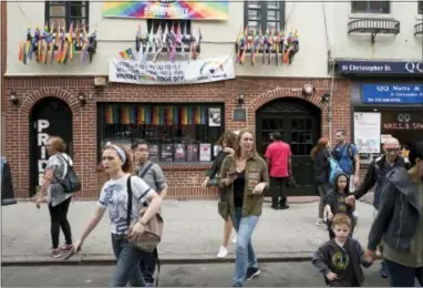  ?? MARK LENNIHAN — THE ASSOCIATED PRESS FILE ?? In this file photo, people pass the Stonewall Inn in New York. Riots took place at the Stonewall Inn after a police raid in 1969, and a park across the street is now a U.S. national monument honoring the birthplace of the LGBT rights movement.