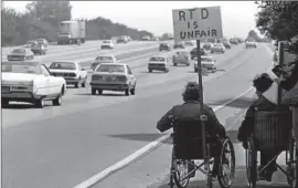  ?? Ken Hively
Los Angeles Times ?? TWO MEN PARTICIPAT­E in a procession along the 101 Freeway in 1981 against the Rapid Transit District bus system, which couldn’t accommodat­e wheelchair­s.