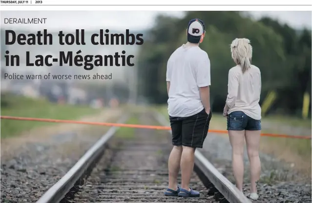  ?? DARIO AYALA/ POSTMEDIA NEWS ?? People look down the train tracks toward the scene of the explosion in the town of Lac- Mégantic on Wednesday . The tragedy has claimed 20 lives, with 30 more people missing.