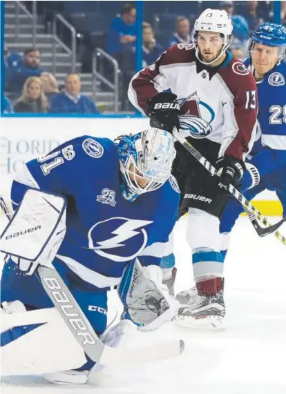  ?? Chris O’Meara, The Associated Press ?? Lightning goaltender Peter Budaj makes a glove save with the Avalanche’s Alexander Kerfoot nearby during Thursday’s game in Tampa, Fla. Budaj, a former Avs goalie, made 28 saves in the Lightning’s 5-2 win.