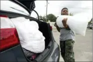  ?? JOSHUA BOUCHER/NEWS HERALD VIA AP ?? Xavier McKenzie puts a 20-pound bag of ice into his family’s car in Panama City, Fla., as Hurricane Michael approaches on Tuesday, Oct. 9. He and his family do not live in a storm surge area, and instead prepared for losing power for days.