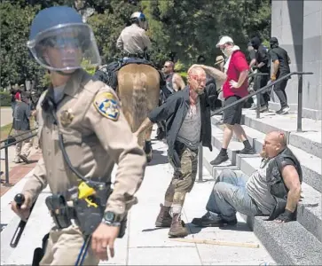  ?? Paul Kitagaki Jr. Associated Press ?? AN INJURED MAN stands next to another on the steps of the state Capitol in Sacramento after a neo-Nazi group and counter-protesters clashed at a rally in June. Seven people were stabbed in the confrontat­ion.