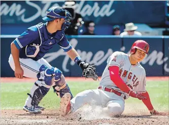  ?? NATHAN DENETTE THE CANADIAN PRESS ?? Los Angeles Angels designated hitter Shohei Ohtani scores under the tag of Blue Jays catcher Luke Maile in the ninth inning in Toronto on Thursday afternoon. The Angels thumped the Blue Jays in all aspects of the game.