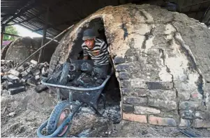  ??  ?? Finished product: A worker collecting charcoal from a gok at Kampung Kolam in Setiu. — Bernama