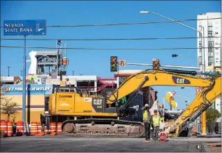  ?? STEVE MARCUS ?? Traffic controller­s stand by an excavator while roadwork is done Dec. 22 on Las Vegas Boulevard at Bridger Avenue in downtown Las Vegas.