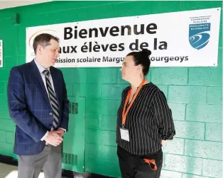  ?? JOHN MAHONEY ?? Riverdale High School principal Mat Canavan speaks with Marie Émond, of the Marguerite-Bourgeoys school board, near a poster welcoming immigrant students who could not find space in French schools.