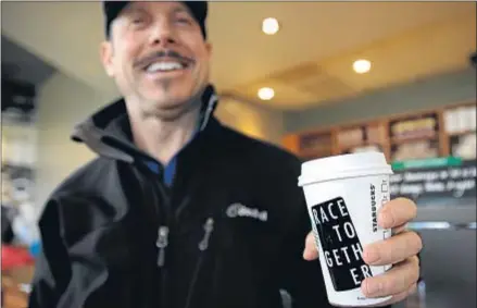  ?? AP ?? Matt Ullman sostiene un vaso de café con el lema ‘Race Together’ en un local de Starbucks en Seattle