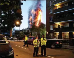  ?? DANIEL LEAL-OLIVAS/AFP ?? Police man a security cordon as a huge fire engulfs the Grenfell Tower early June 14, 2017, in west London.