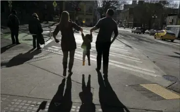  ??  ?? In this March 3, 2015, file photo, a child is lifted by her parents at a street corner in downtown Seattle. The expansion of a child tax credit helped seal Congress’ approval of the Republican tax overhaul. AP PHOTO/TED S. WARREN