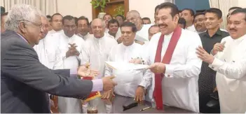  ?? — AFP ?? Sri Lanka’s newly appointed prime minister Mahinda Rajapaksa hands a signed document to his secretary Sirisena Amarasekar­a during a ceremony to assume duties at the prime minister’s office in Colombo on Monday.