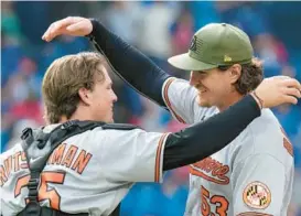  ?? FRANK GUNN/AP ?? Orioles reliever Mike Baumann, right, and catcher Adley Rutschman hug after an 8-3 win over the Blue Jays on Sunday in Toronto.