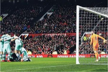  ?? AP ?? Arsenal players hug teammate Alexandre Lacazette (left) who had a role in his side’s second goal, scored by Manchester United defender Marcos Rojo (not pictured), as United’s goalkeeper David de Gea (right) picks the ball out of the net, during their English Premier League match at Old Trafford stadium in Manchester, England, yesterday.