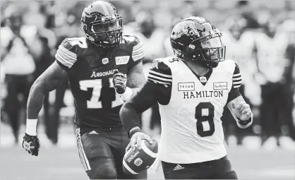  ?? COLE BURSTON THE CANADIAN PRESS ?? Argonauts defensive end Rakim Cox, left, chases down Hamilton Tiger-Cats quarterbac­k Jeremiah Masoli during second-half CFL action in Toronto on Saturday. Masoli threw four touchdown passes as the Ticats prevailed in the contest, 36-25.