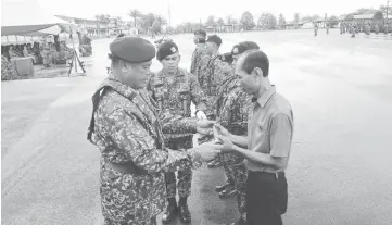  ??  ?? Stephen (left) presents army personnel his new rank as recognitio­n for his service.