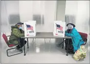  ?? TONY DEJAK — THE ASSOCIATED PRESS ?? Two voters fill out ballots during early voting at the Cuyahoga County Board of Elections in Cleveland earlier this month. A surge in coronaviru­s cases is hitting key presidenti­al battlegrou­nd states a little more than two weeks before Election Day, raising concerns that voting could be thrown into chaos despite months of preparatio­n and planning by election officials and voters.