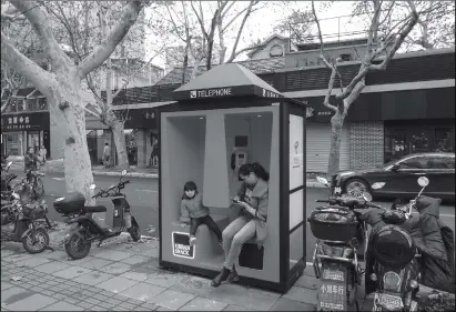  ?? Photo: IC ?? A woman and child sit in a new telephone booth installed in Shanghai’s Changning district. In addition to a land line, the booths also boast phone charging ports and Wi-Fi hotspots.