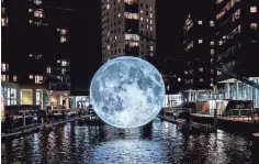  ?? LEEDS LIVING ?? Museum of the Moon, a 23-foot inflatable moon made with NASA images, hangs over the water at Leeds Dock in England. The artwork is coming to Milwaukee this weekend.