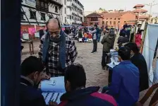 ?? Niranjan Shrestha/Associated Press ?? Election workers check voter records during parliament­ary balloting at a polling station in Nepal’s capital of Kathmandu.