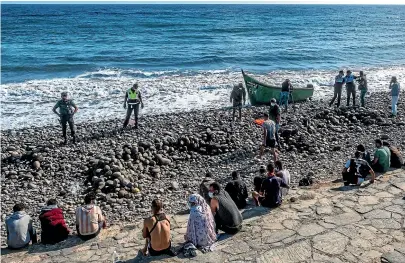  ?? AP ?? Migrants, most of them from Morocco, are watched by Spanish police after arriving at the coast of the Canary Islands.
