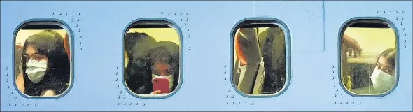  ?? AFP ?? Passengers look out of the windows of a Boeing 737-31S Kam Air passenger plane with people evacuated from Afghanista­n, at Boryspil Internatio­nal Airport outside Kiev, Ukraine.