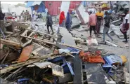  ?? AP PHOTO/FARAH ABDI WARSAMEH ?? People look at destroyed shops at Lido beach in Mogadishu, Somalia, on April 23, after a bomb blast by Somalia’s Islamic extremist rebels hit a popular seaside restaurant, killing at least six people.