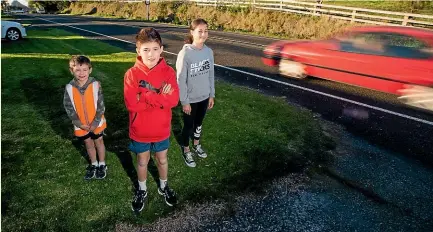  ?? SIMON O’CONNOR/STUFF ?? Benjamin Withers, 10 (centre), with brother Ethan, 7, and sister Natalie, 12, wants the speed limit in Omata reduced from 80kmh to 50kmh.