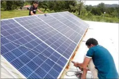  ?? HENG CHIVOAN ?? Men install solar panels at their home in Preah Sihanouk province.