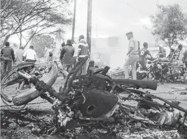  ?? Associated Press ?? Destroyed motorbikes and debris litter the scene as a victim is carried away after a gasoline tanker exploded on Saturday in Morogoro, Tanzania, one of the worst incidents of its kind in the east African country.