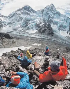  ?? FOTO: DPA ?? Eine Gruppe von Touristen auf der Felsenplat­tform Kala Patar genießt in 5545 Meter Höhe den Blick auf die Everest-Gruppe: Der Aufstieg zum höchsten Berg der Welt ist extrem riskant.