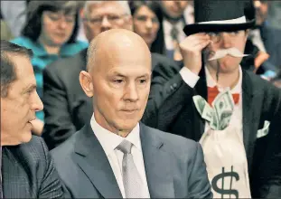  ??  ?? MAD (AS IN ANGRY) HATTER: A woman dressed like the Monopoly mascot sits behind ex-Equifax CEO Richard Smith Wednesday to dramatize the case for consumer protection.