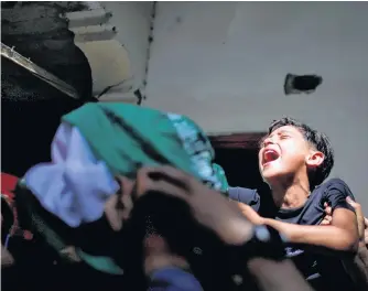  ?? REUTERS ?? The brother of Palestinia­n man Ahmed Al-shenbari, who was killed amid a flare-up of Israelipal­estinian violence, reacts as mourners carry his body during his funeral in the northern Gaza Strip on Tuesday.