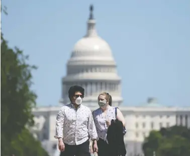  ?? SARAH SILBIGER / GETTY IMAGES ?? People walk on the National Mall in Washington, D.C., on Saturday. Earlier in the day thousands gathered at the site to watch a U.S. navy flyover to honour health-care workers and others battling the pandemic.