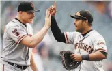  ?? David Zalubowski / Associated Press ?? Above, reliever Mark Melancon (left) is met by shortstop Donovan Solano at game’s end.