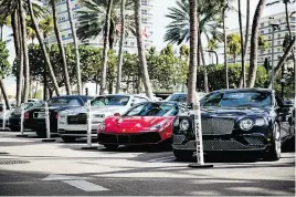 ??  ?? Luxury cars are parked amid the palm trees in the valet area of Bal Harbour Shops