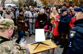  ?? LYNSEY ADDARIO/NEW YORK TIMES ?? Ukrainians gathered around a Starlink satellite antenna for internet connection in Kherson, Ukraine, in November.