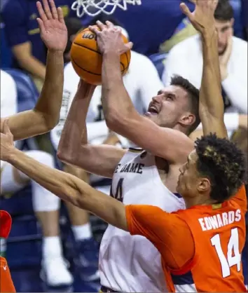  ?? Associated Press ?? TOUGH SHOT Notre Dame’s Nate Laszewsk forces his way toward the basket against two Syracuse defenders Saturday in Notre Dame, Ind. Jesse Edwards and Joe Girard combined for 42 points as Syracuse beat Notre Dame, 62-61, in the ACC opener for both teams.