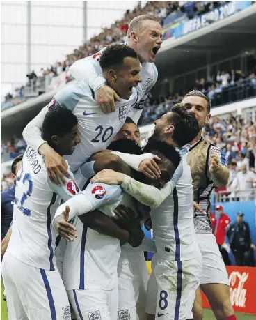  ?? KIRSTY WIGGLESWOR­TH / THE ASSOCIATED PRESS ?? England’s Daniel Sturridge, centre, is mobbed by teammates after scoring the winning goal in their 2-1 victory over Wales in Group B action at Euro 2016 on Thursday.
