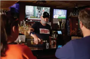  ?? JEFF ROBERSON THE ASSOCIATED PRESS ?? Bartender Greg Anderson pours drinks for customers on Monday, the first day Tuner’s Bar and Grill reopened after being closed to slow the spread of the coronaviru­s, in St. Charles, Mo.