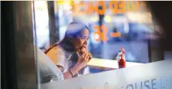  ?? (Steven Saphore/Reuters) ?? A WOMAN eats a burger at a fast-food restaurant in Sydney.