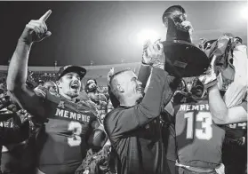  ?? Mark Humphrey / Associated Press ?? Memphis quarterbac­k Brady White (3) celebrates as head coach Mike Norvell, center, lifts the trophy after the Tigers beat Cincinnati for the AAC title.