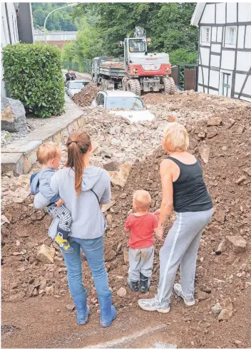  ?? FOTO: JULIAN STRATENSCH­ULTE/DPA ?? Passantinn­en stehen nach dem Unwetter an einer mit Geröll übersäten Straße in Hagen.