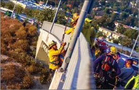  ?? Austin Dave/ The Signal ?? A Los Angeles County firefighte­r holds onto a man found clinging to the side of the Whites Canyon Road bridge over the Santa Clara River in Canyon Country.