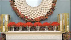  ?? Biz Jones ?? Alexa Hampton decorated the new Moorish-influenced honed limestone Castello mantel she designed for Chesney’s with five simple shiny silver vessels filled with red roses. Draping the back is a garland of pine cones and red berries, which also borders...