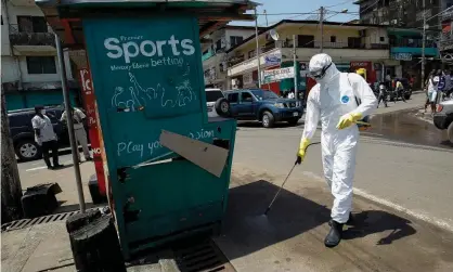  ?? Photograph: Ahmed Jallanzo/EPA ?? A health worker disinfects a street corner where a suspected Ebola patient was picked up and taken into an ambulance in Monrovia, Liberia in 2014.