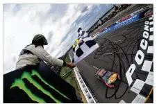  ?? JARED C. TILTON / GETTY IMAGES ?? Martin TruexJr., driver of the No. 78Toyota, takes thechecker­ed flag Sunday to win the NASCAR Cup Series Pocono 400 in Long Pond, Pennsylvan­ia.