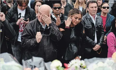  ?? GALIT RODAN THE CANADIAN PRESS ?? People wipe their tears at a memorial on Yonge Street Tuesday, the day after a driver drove a rented van down sidewalks striking pedestrian­s in his path in Toronto.