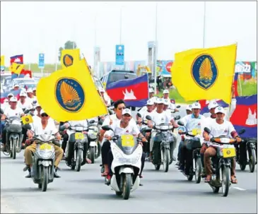  ?? HENG CHIVOAN ?? Funcinpec supporters ride motorbikes and wave flags during their party’s parade in the capital on July 7.