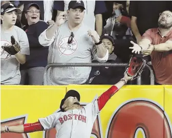  ?? AP PHOTO ?? REACHING OUT: Red Sox right fielder Mookie Betts vies with a fan for a ball hit by the Yankees’ Chris Carter during the seventh inning of last night’s game in New York. The ball hit the fan’s hands but Betts caught it for the out.