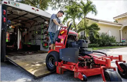  ?? PHOTOS BY RICHARD GRAULICH / THE PALM BEACH POST ?? Austyn Roth, 15, who runs his own landscapin­g business in Jupiter, puts away one of his mowers last month. The Jupiter High School freshman attends trade shows around the country and hires two adults to drive his company’s truck.